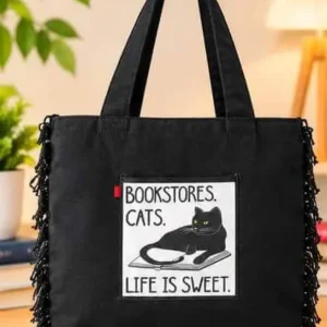 Sabuj Hub black canvas tote bag featuring Bookstore Cats Life is Sweet graphic patch and fringe trim details